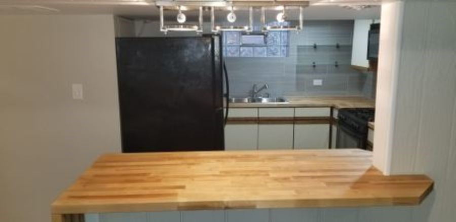 A kitchen with a black refrigerator and wooden countertop.
