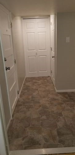 A hallway with a white door and a tiled floor.
