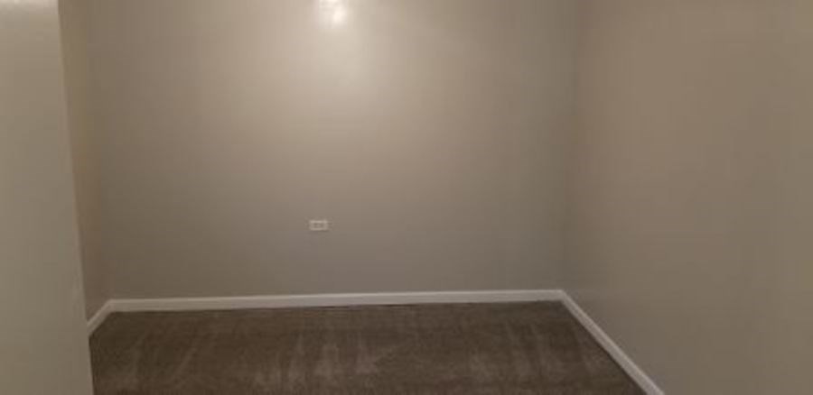 A room with a brown floor and white walls.