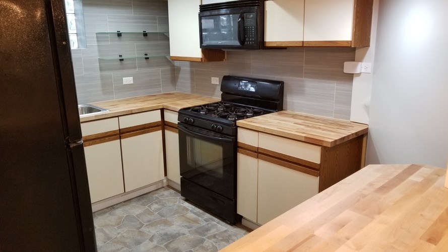 A kitchen with a black oven and wooden countertops.