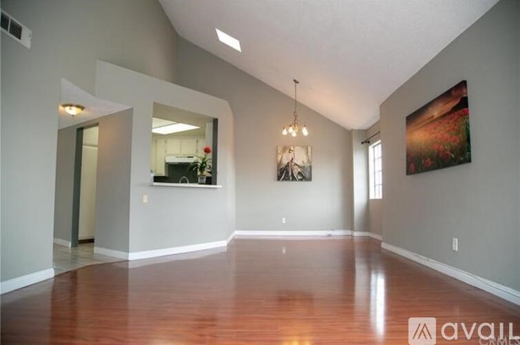 A spacious room with wooden floors and a large painting on the wall.