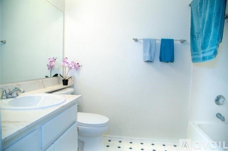 A white bathroom with a white toilet, sink, and a blue towel hanging on the wall.