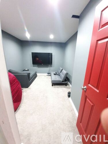 A living room with a red door and a grey couch.
