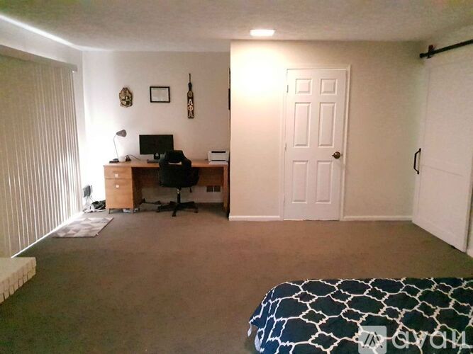 A bedroom with a bed, desk, and chair.