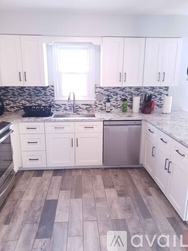 A kitchen with white cabinets and a marble backsplash.