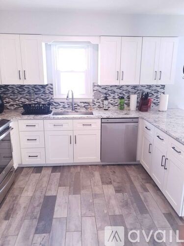 A kitchen with white cabinets and a marble backsplash.