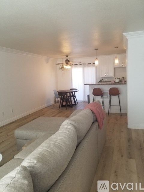 A living room with a grey couch and a dining area in the background.
