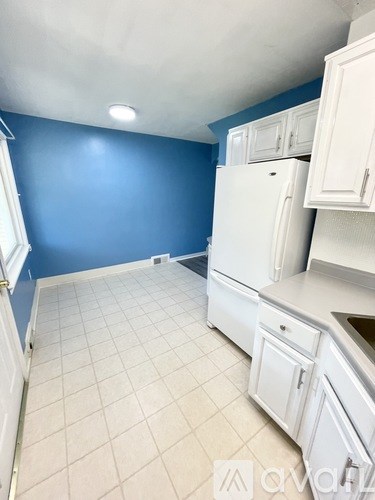 A kitchen with white cabinets and a white refrigerator.