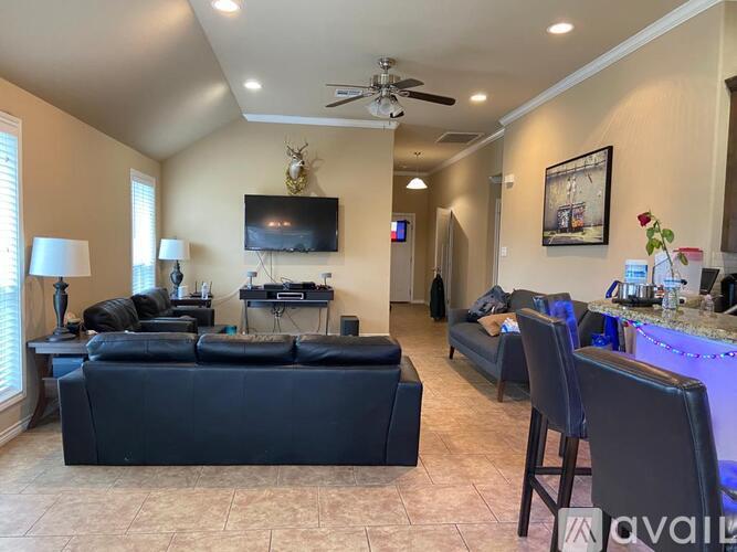 A living room with a black couch and a television on the wall.