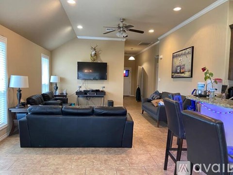 A living room with a black couch and a television on the wall.