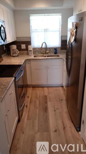 A kitchen with wooden floors and white cabinets.