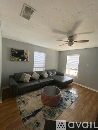 A living room with a grey couch and a ceiling fan.