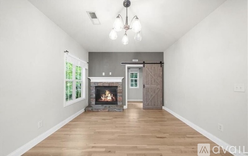 A spacious room with a fireplace and wooden flooring.
