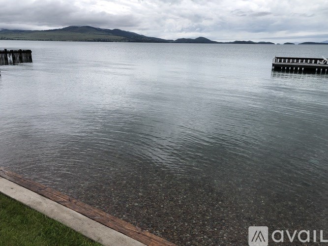 A calm body of water with a dock and mountains in the distance.