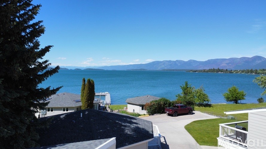 A red car is parked on a driveway in front of a house.