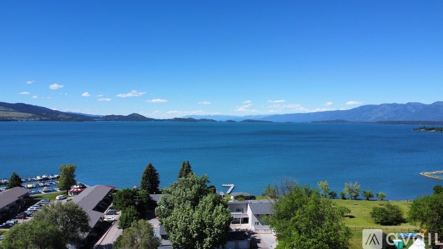 A view of a lake with a mountain range in the background and a parking lot in the foreground.