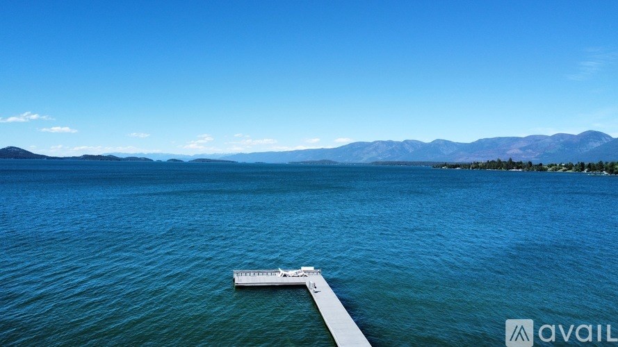 A calm body of water with a dock and mountains in the distance.