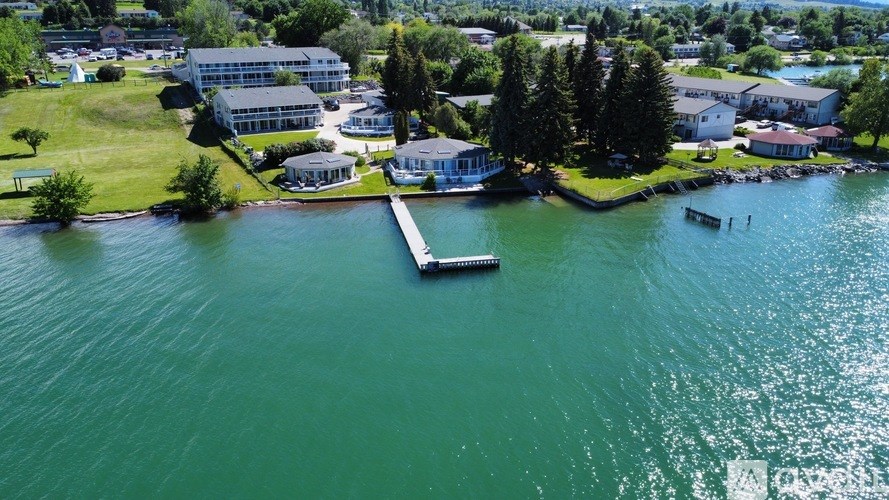 A large body of water with a dock and a house on the shore.
