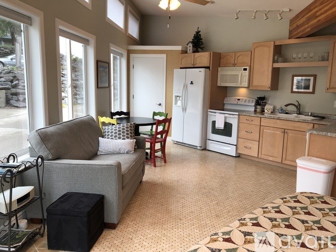 A kitchen with a white fridge and a grey couch.