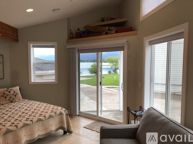 A bedroom with a bed, a couch, and a view of the backyard through the sliding glass doors.