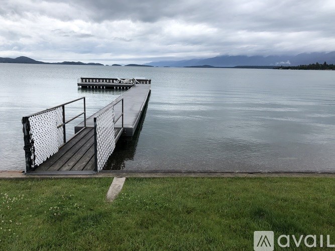 A dock extends into a lake with a cloudy sky overhead.