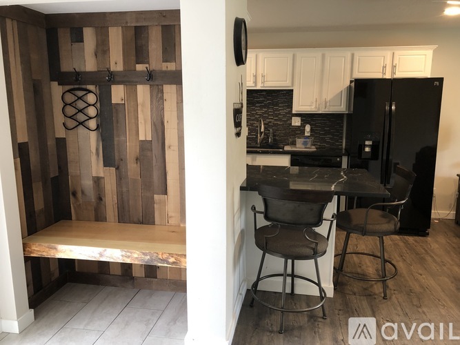 A kitchen with a black fridge and a wooden wall.