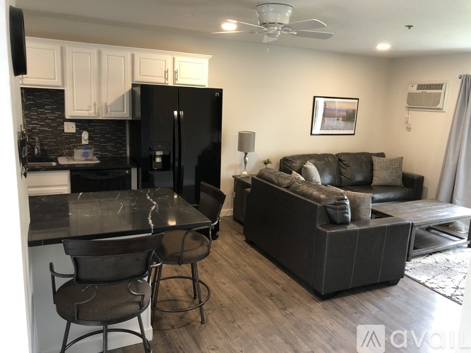 A kitchen with a black fridge and a black table with two chairs.