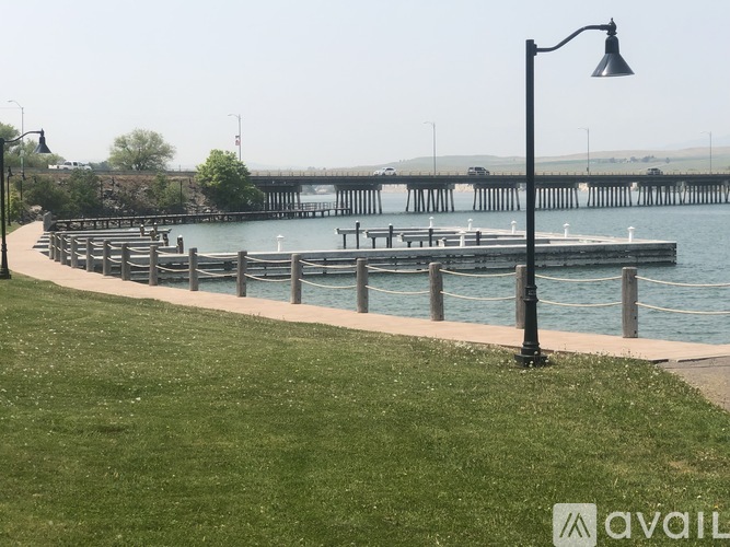 A grassy area with a lamp post and a pier in the background.