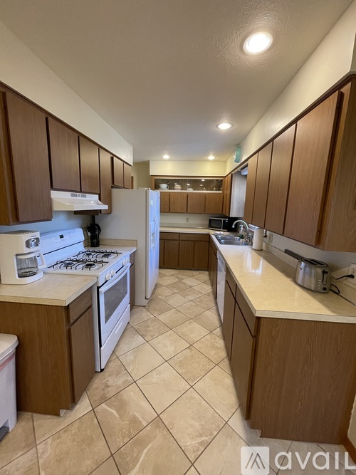 A kitchen with brown cabinets and white appliances.