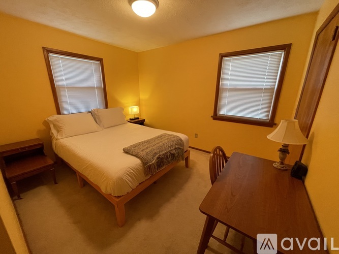 A bedroom with a bed, a table, and a chair.
