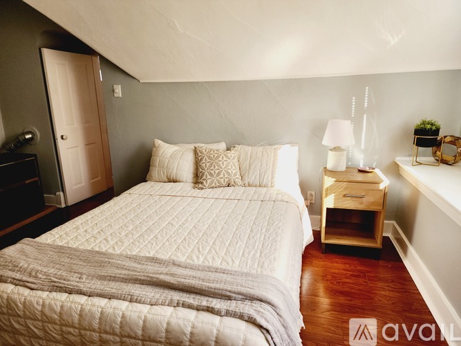 A bedroom with a large bed and a lamp on a side table.