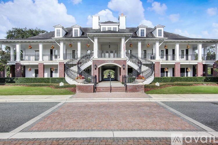 A large white house with a black roof and a brick walkway in front.