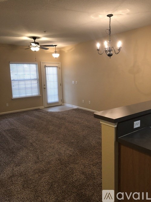 A room with a carpeted floor, a ceiling fan, and a chandelier.