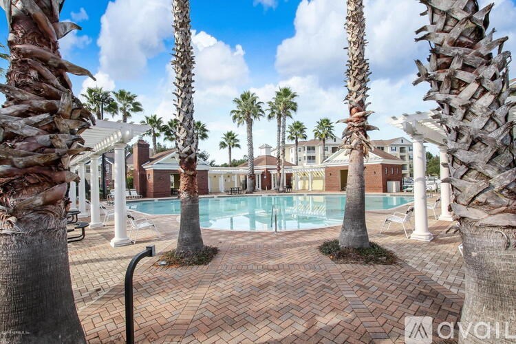 A pool surrounded by palm trees and concrete pillars.