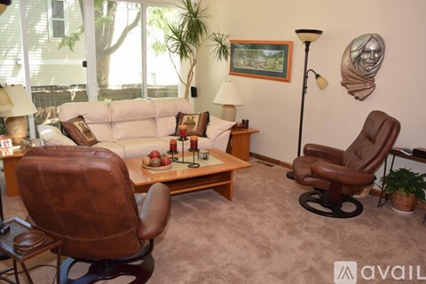 A living room with a brown leather chair and a white couch.
