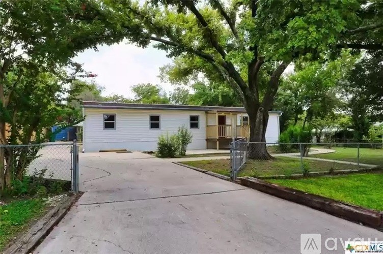 A white house with a fence and trees around it.