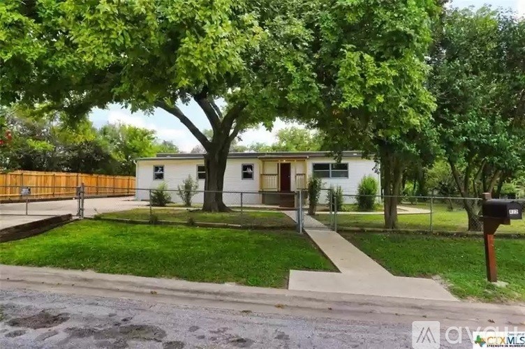 A white house with a brown fence and a mailbox in front.
