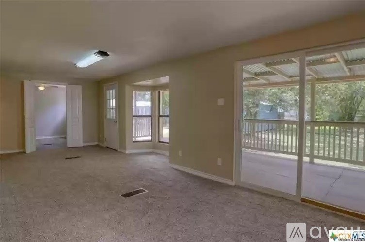 A spacious room with a sliding glass door leading to a balcony.