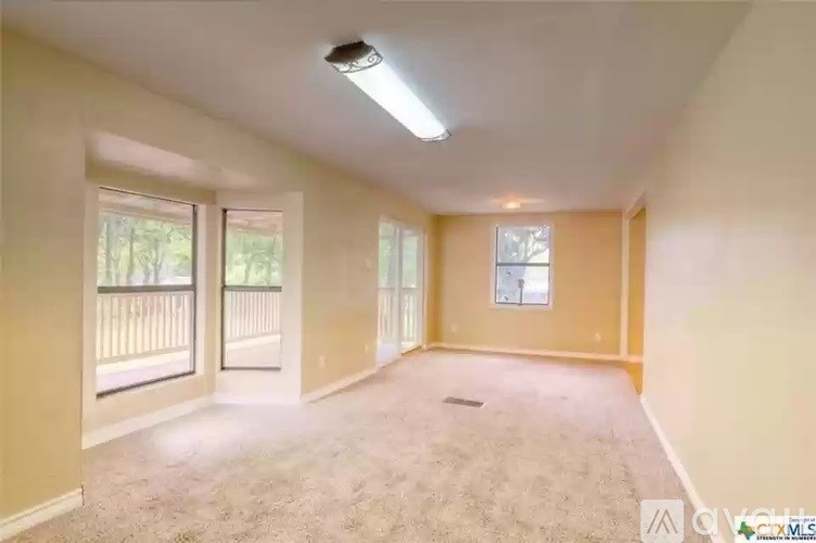 A spacious room with a carpeted floor and a window overlooking a balcony.