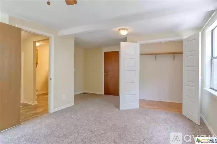 A spacious room with a carpeted floor and white walls.