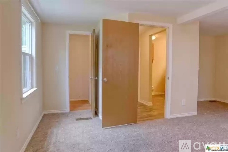 A room with a carpeted floor and a wooden door.
