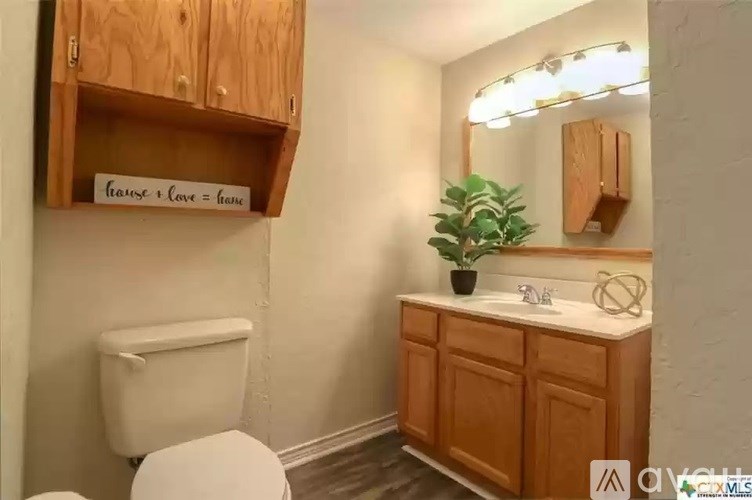 A bathroom with a toilet, sink, and wooden cabinets.