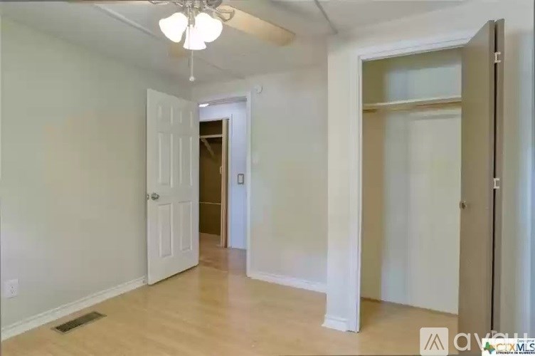 A room with a white door and a ceiling fan.