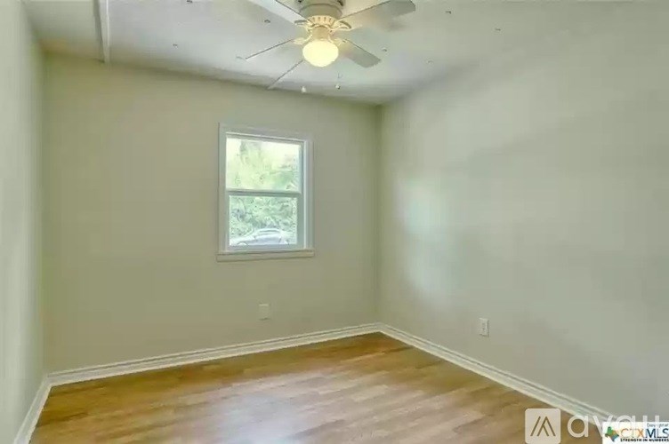 A room with a ceiling fan and a window.