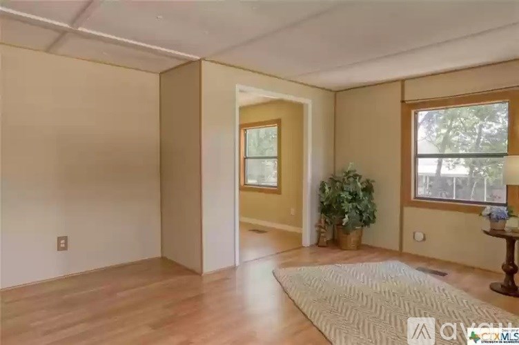 A room with a rug on the floor and a plant on the side table.