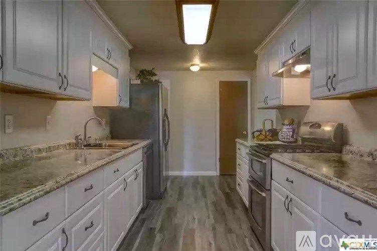 A kitchen with white cabinets and a granite countertop.
