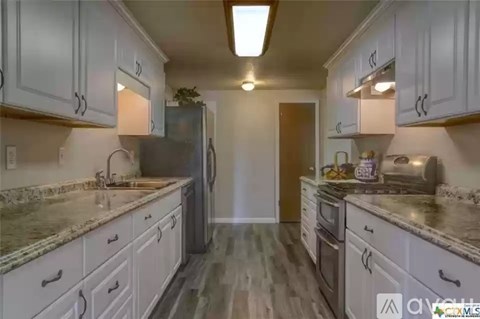 A kitchen with white cabinets and a granite countertop.