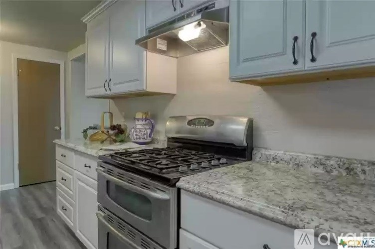 A kitchen with a granite countertop and white cabinets.