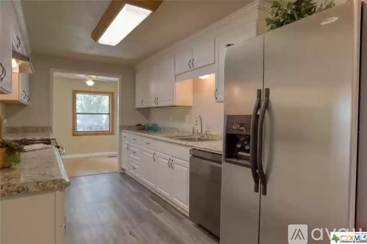 A kitchen with white cabinets and a stainless steel refrigerator.
