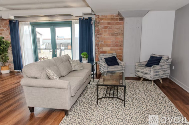 A living room with a grey couch, two chairs, and a patterned rug.